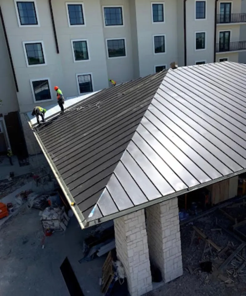 Crew installing standing seam metal roof panels on a commercial project in Esopus